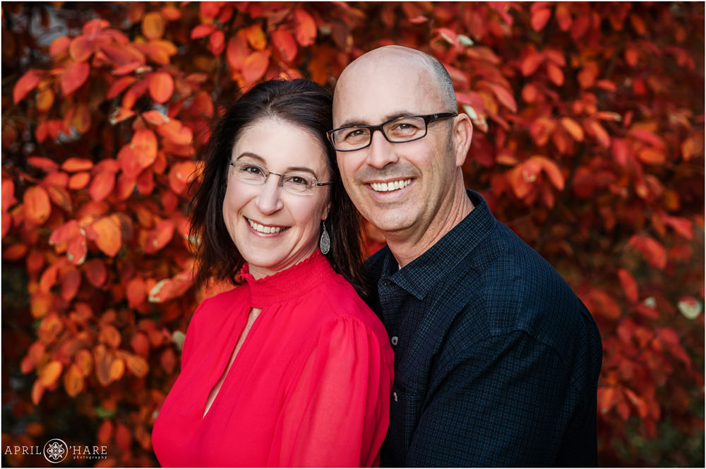 Parents of a bar mitzvah boy get their own portrait in front of pretty red fall color backdrop at the Lincoln Center in Fort Collins