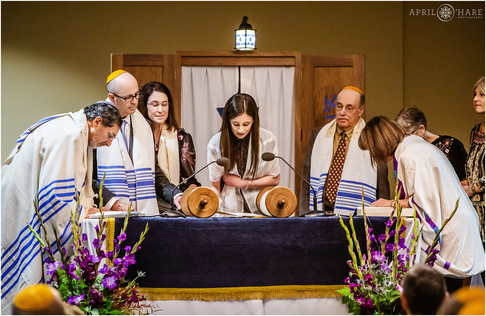 Sister of bar mitzvah boy reads from Torah with family surrounding her at the Lincoln Center in Colorado