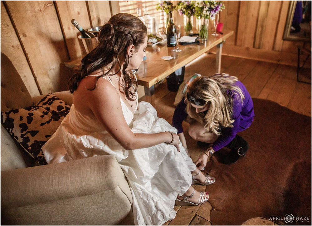 Bride gets some help with her heels on her wedding day at Piney River Ranch in Vail