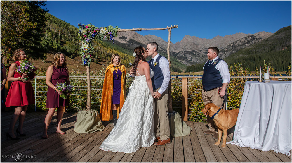 Ceremony kiss at outdoor sunny wedding day on the deck at Piney River Ranch during September