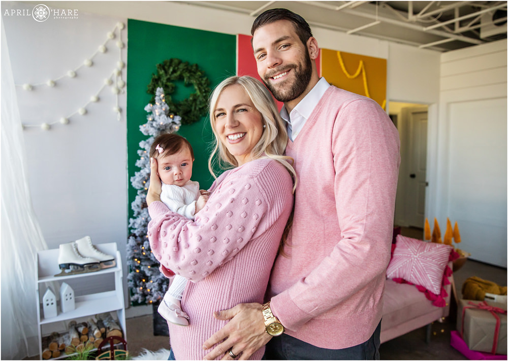 Family wearing pink pose for family pictures in a cold colorful styled set for holiday family pictures in Colorado
