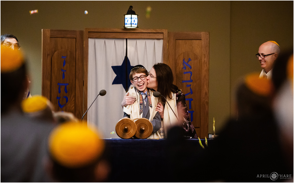 Bar Mitzvah boy has candy thrown at him while his proud mom kisses him at his Bar Mitzvah service in Fort Collins Colorado