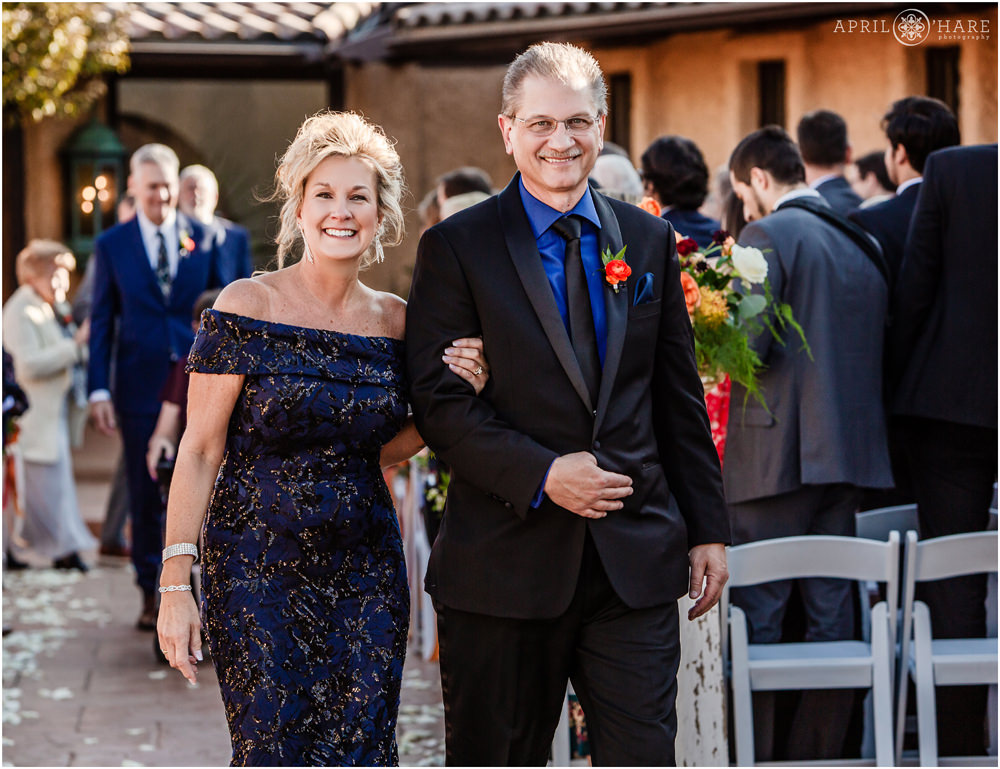 Bride's parents exit wedding ceremony in the courtyard of Villa Parker in Colorado