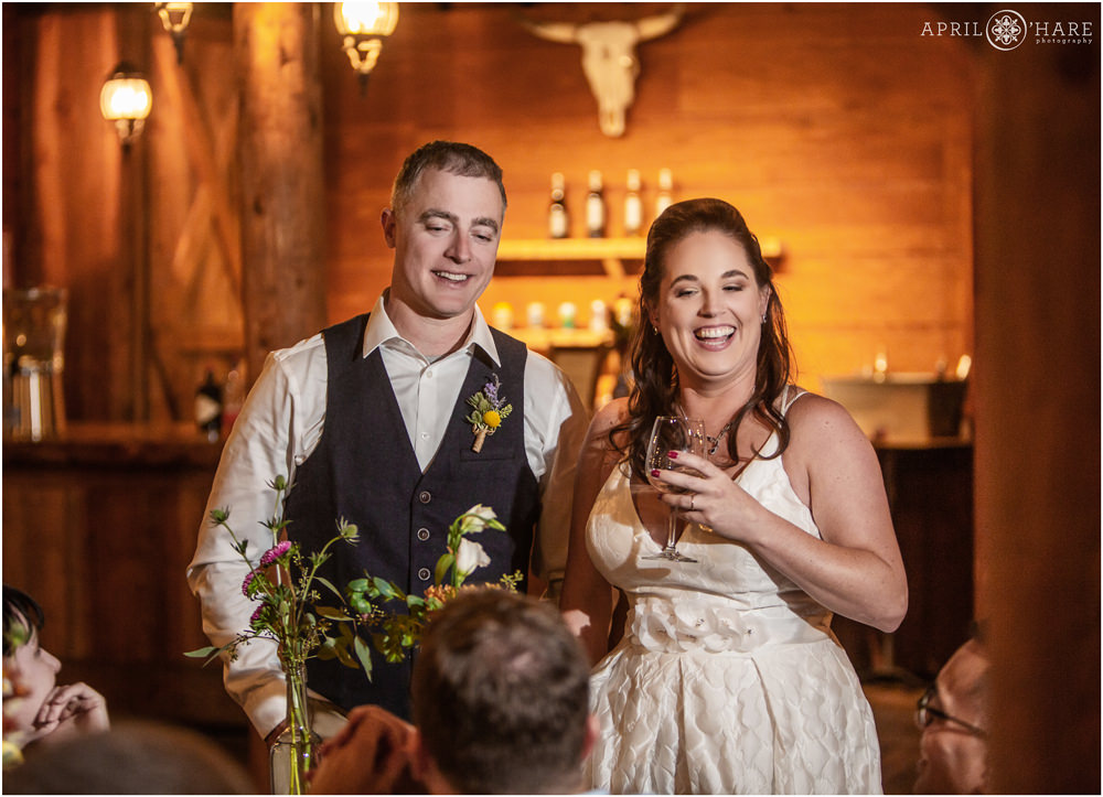 Bride and groom laugh with guests at their rustic Vail wedding in a wood cabin in Colorado