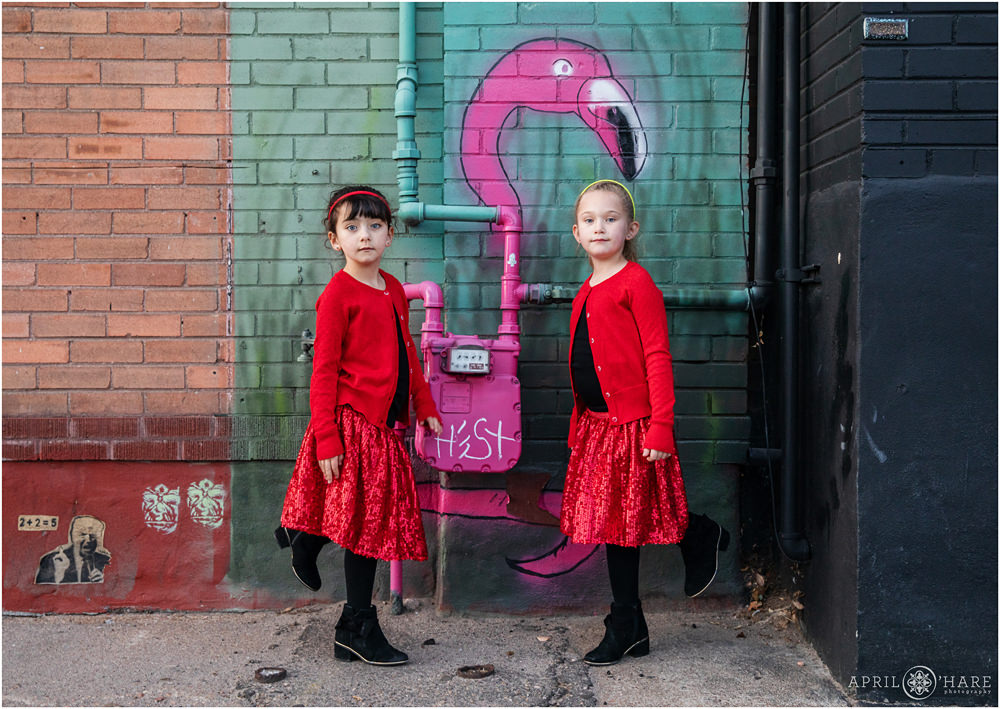 Two young sisters pose as flamingos in Denver Rino Street Art Family Photography Session