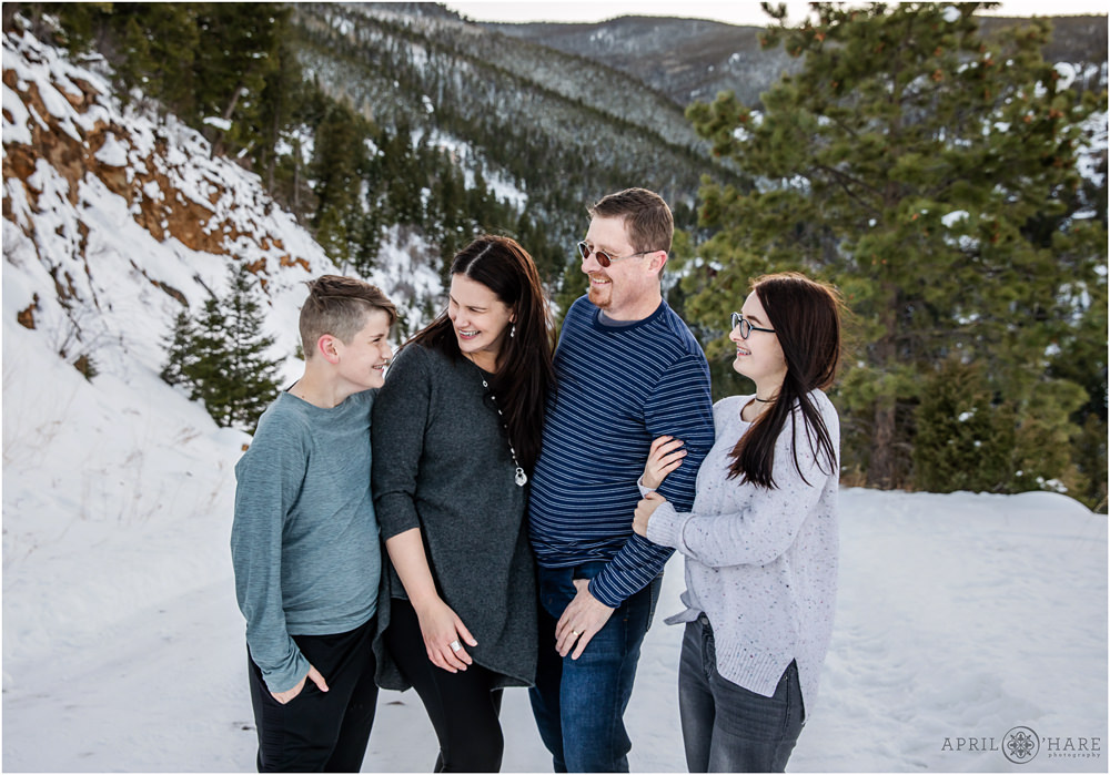 A candid family photo with mountain backdrop in the woods with snow on the ground