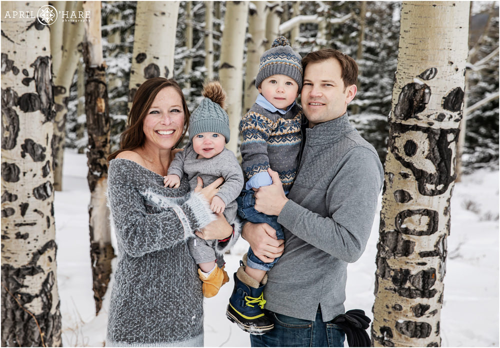 Sweet family wearing gray with a touch of yellow in aspen tree grove during winter in Colorado mountains