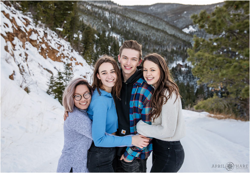 Siblings hug for their family photo in the snow with a pretty snowy Colorado mountain backdrop