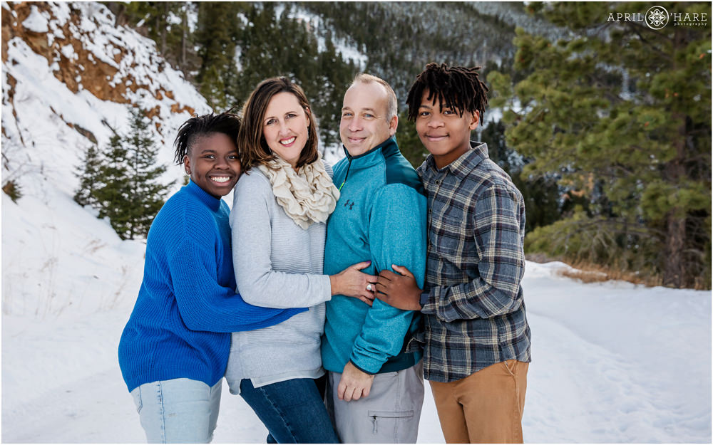 Cute family wearing shades of blue pose for a classic winter wonderland photo in Colorado