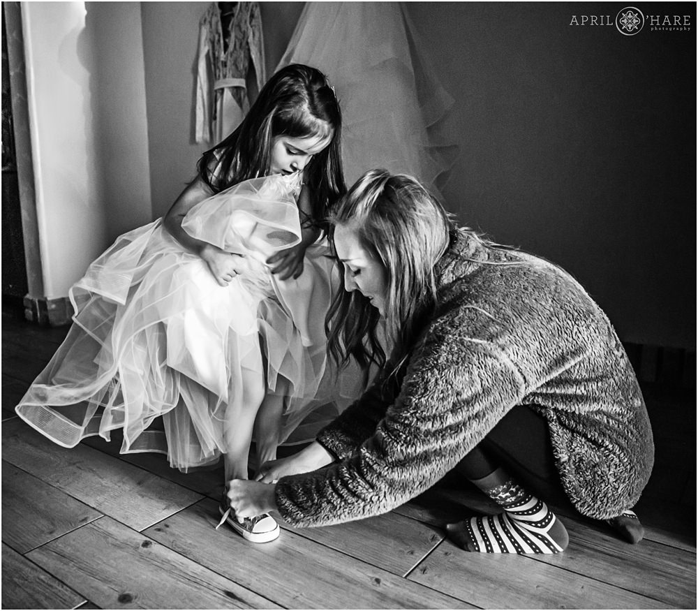 Mom helps her daughter with tying her shoes on her wedding day at Della Terra