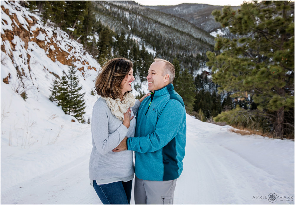 Couple laughs together in a pretty snowy winter wonderland of Colorado during Thanksgiving holiday