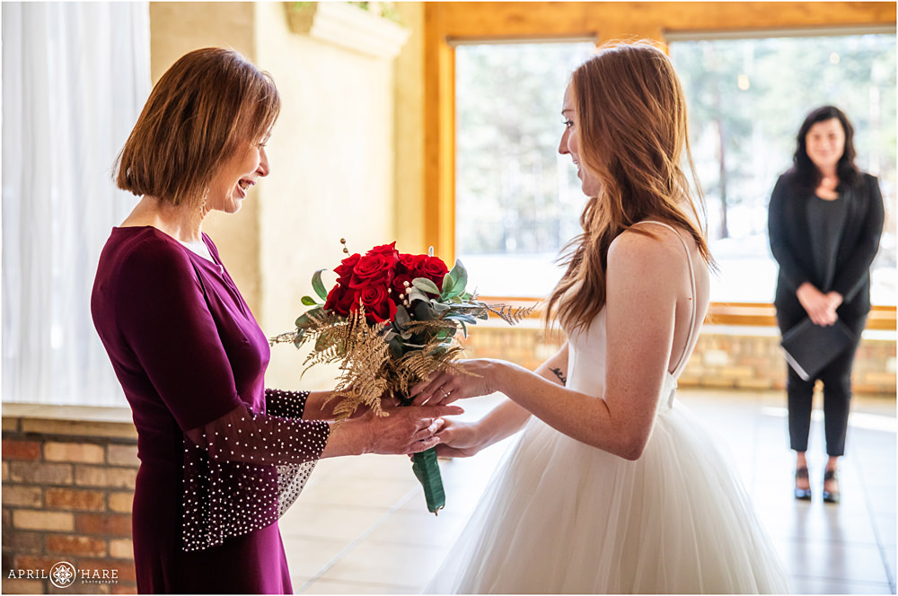 Bride hands her bouquet to her mother in law at Della Terra indoor wedding ceremony