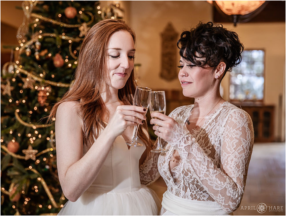 Two brides toast with champagne on their wedding day during Christmas holiday season at Della Terra