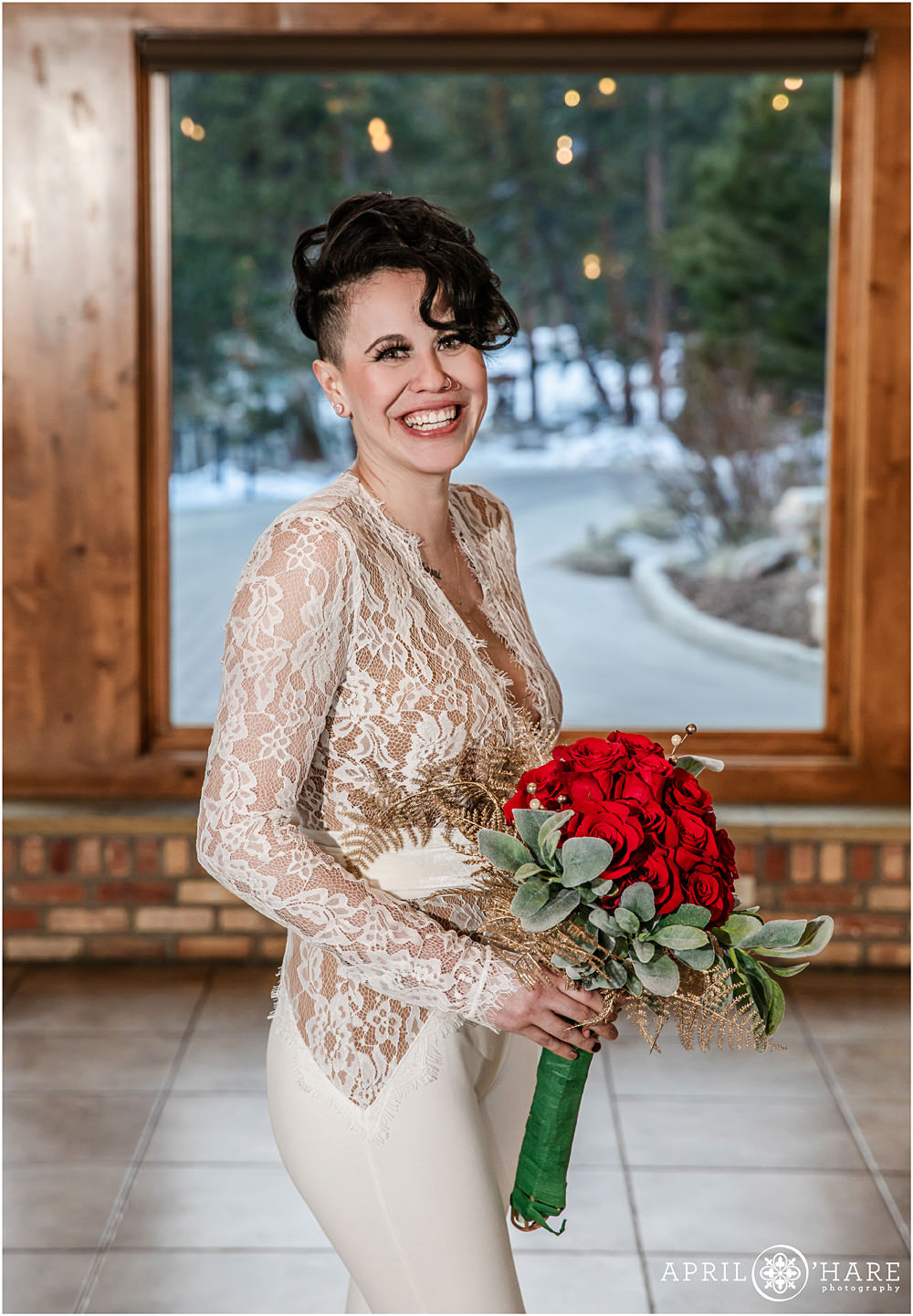Beautiful bride wearing a lace one piece jumpsuit poses for her same sex Christmas Wedding portrait at Della Terra in Estes Park