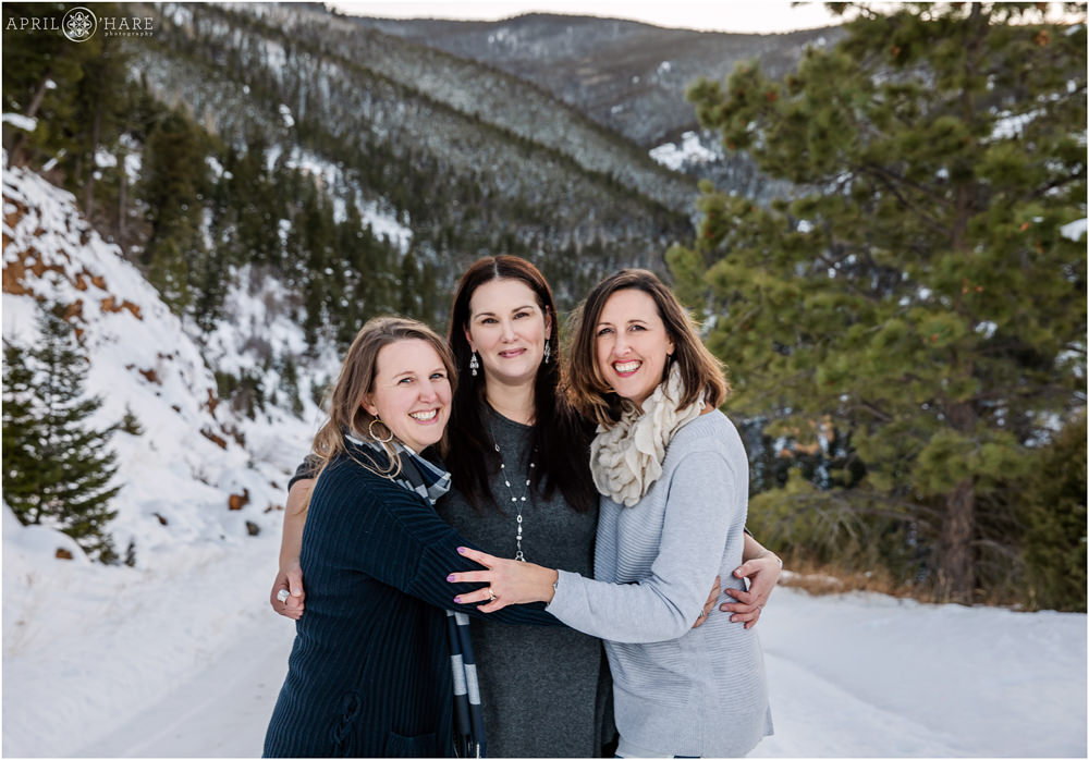 Adult sisters pose for a family photo together in a pretty snowy Colorado mountain environment on Thanksgiving