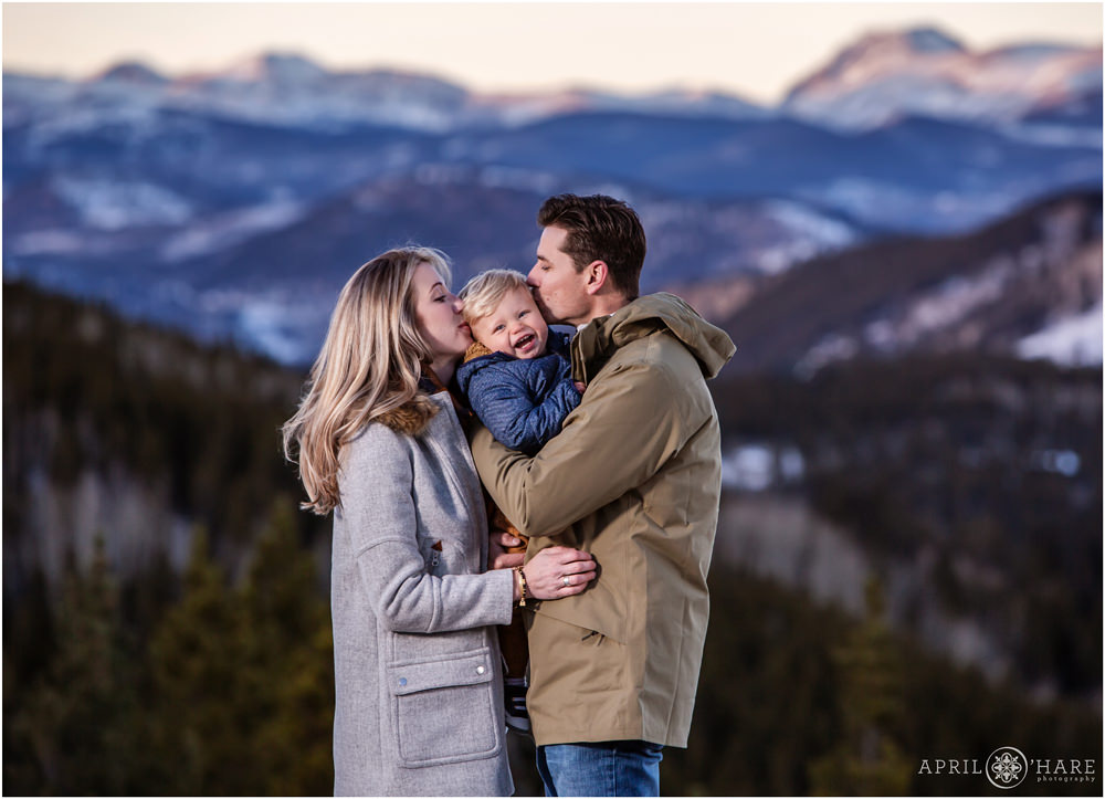Beautiful Sunset Mountain Backdrop for a Family Photo with mom and dad kissing their toddler son