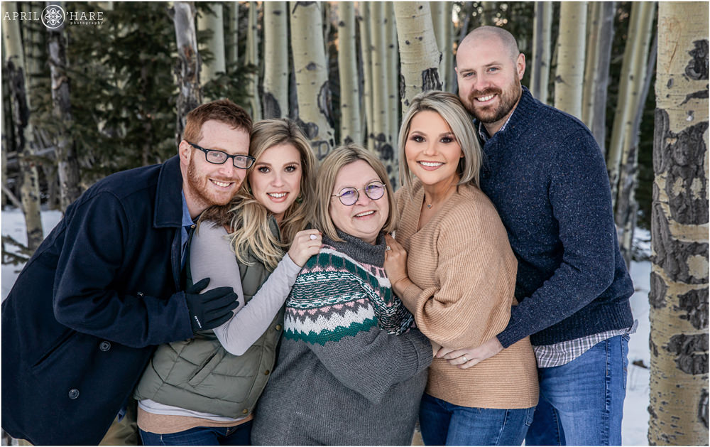 Cuddly family photo during winter in an aspen tree forest in Colorado