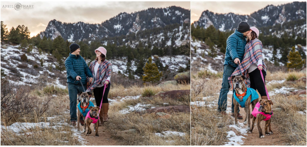 A couple walk down a winter path at the South Mesa Trail in Boulder with their two dogs