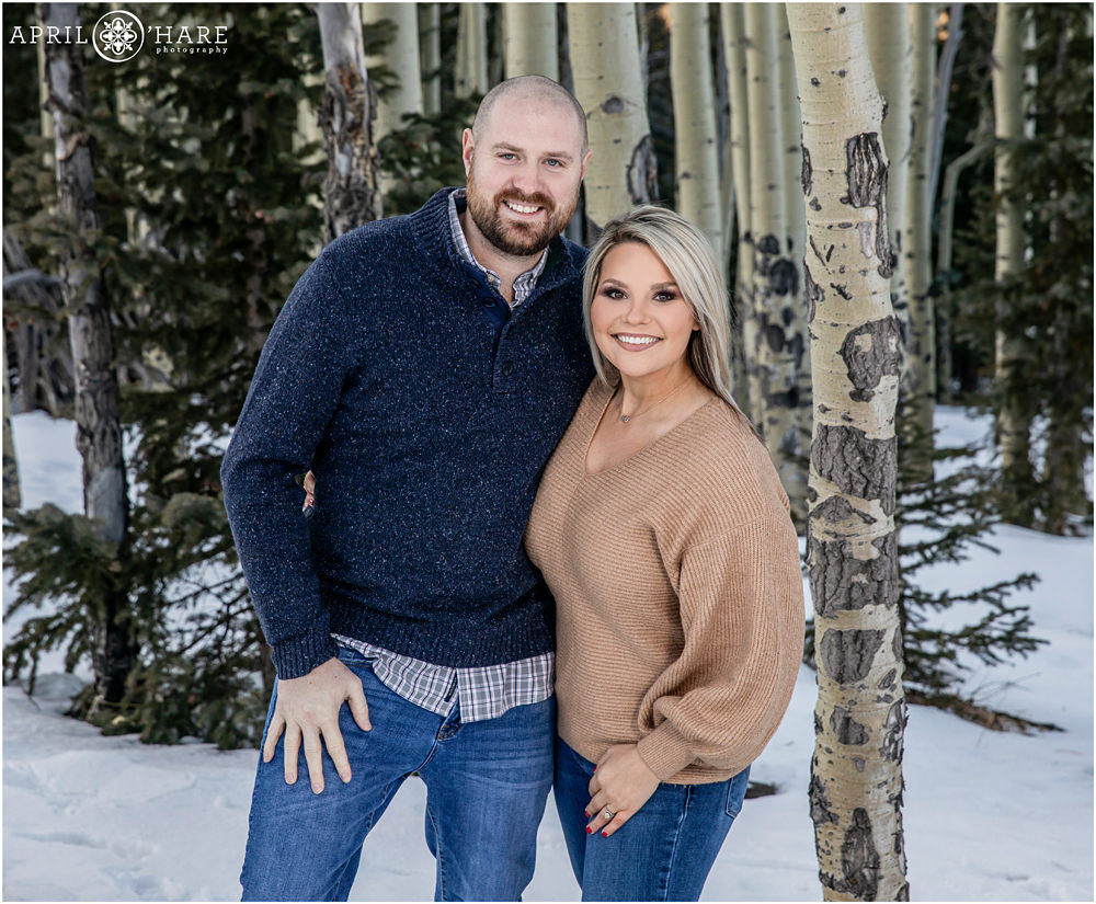 Married couple pose for a pretty winter portrait with aspen tree backdrop