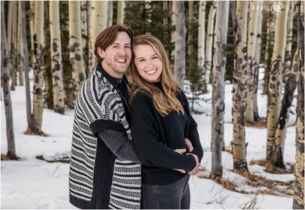 Cute couple wearing black pose in the aspen tree forest on Squaw Pass Road during winter