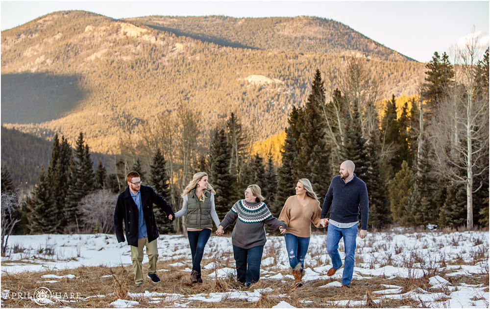 A family holds hands and walks through a mountain meadow in Evergreen Colorado