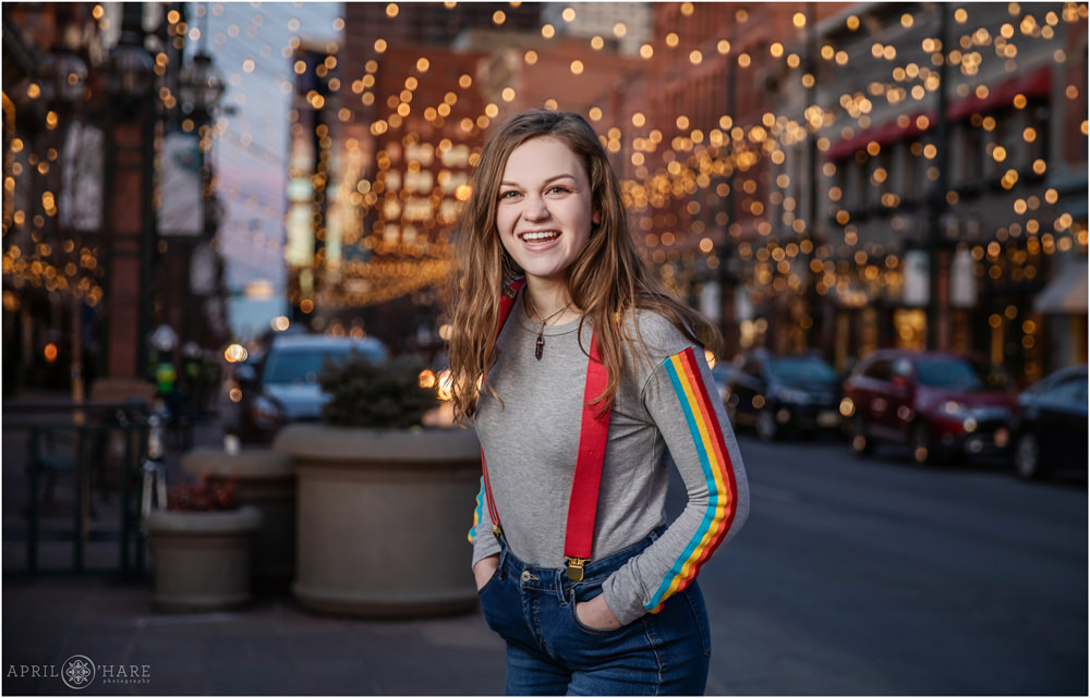 Happy senior portrait of a girl wearing rainbow striped shirt with red suspenders in Denver CO