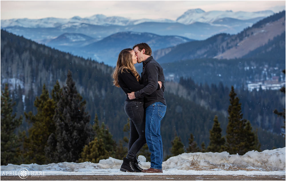 Young couple kisses in a magical holiday winter snow mountain scene on Squaw Pass Road