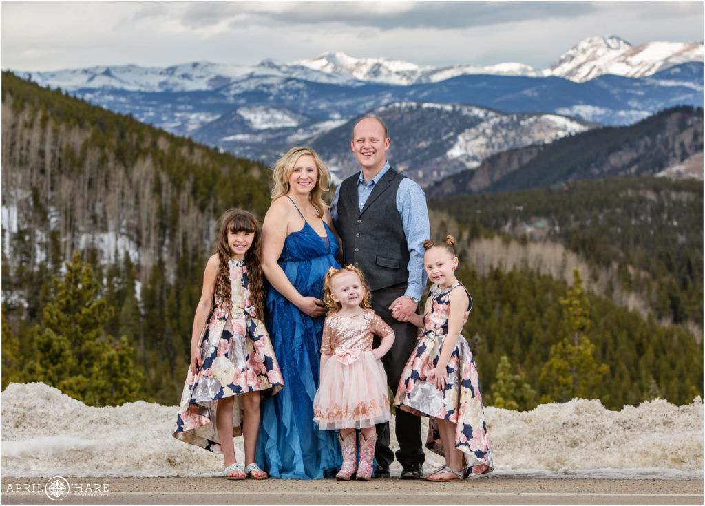 Family of 5 with 3 daughters pose in front of mountain view at Colorado maternity session
