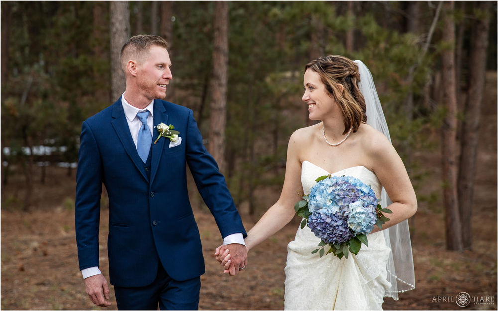 Couple walks in the Black Forest Woods in Colorado Springs at their wedding