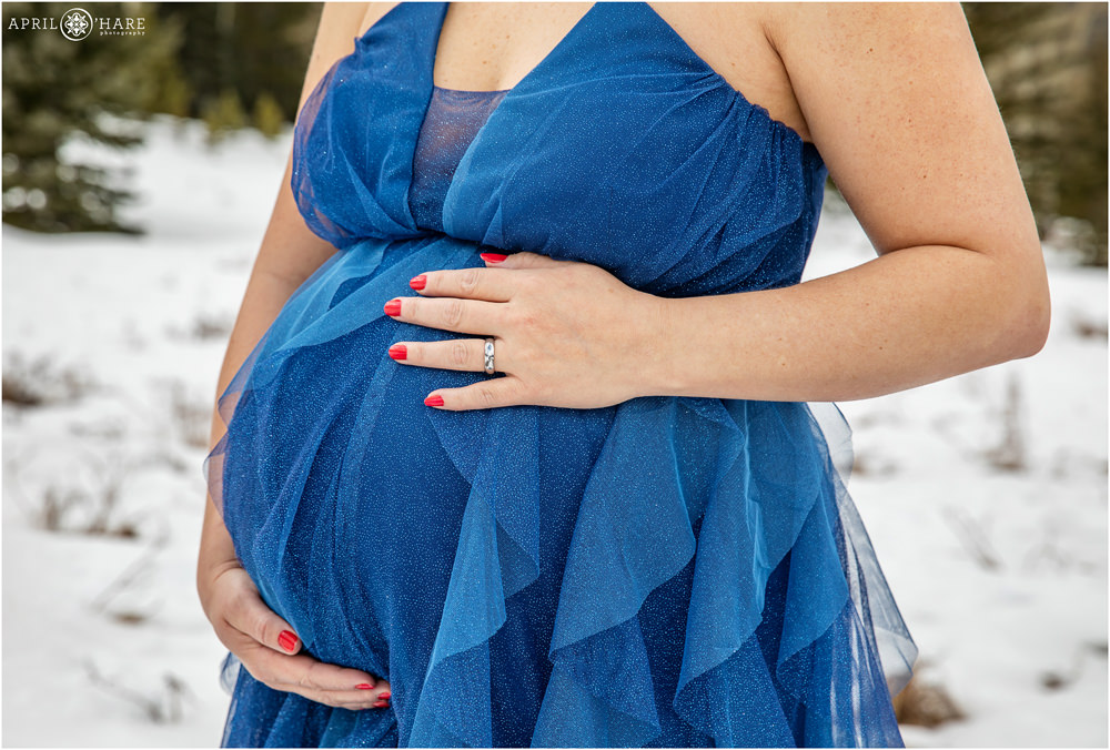 Cute close up photo of a pregnant woman's belly at her maternity photography session in the snow