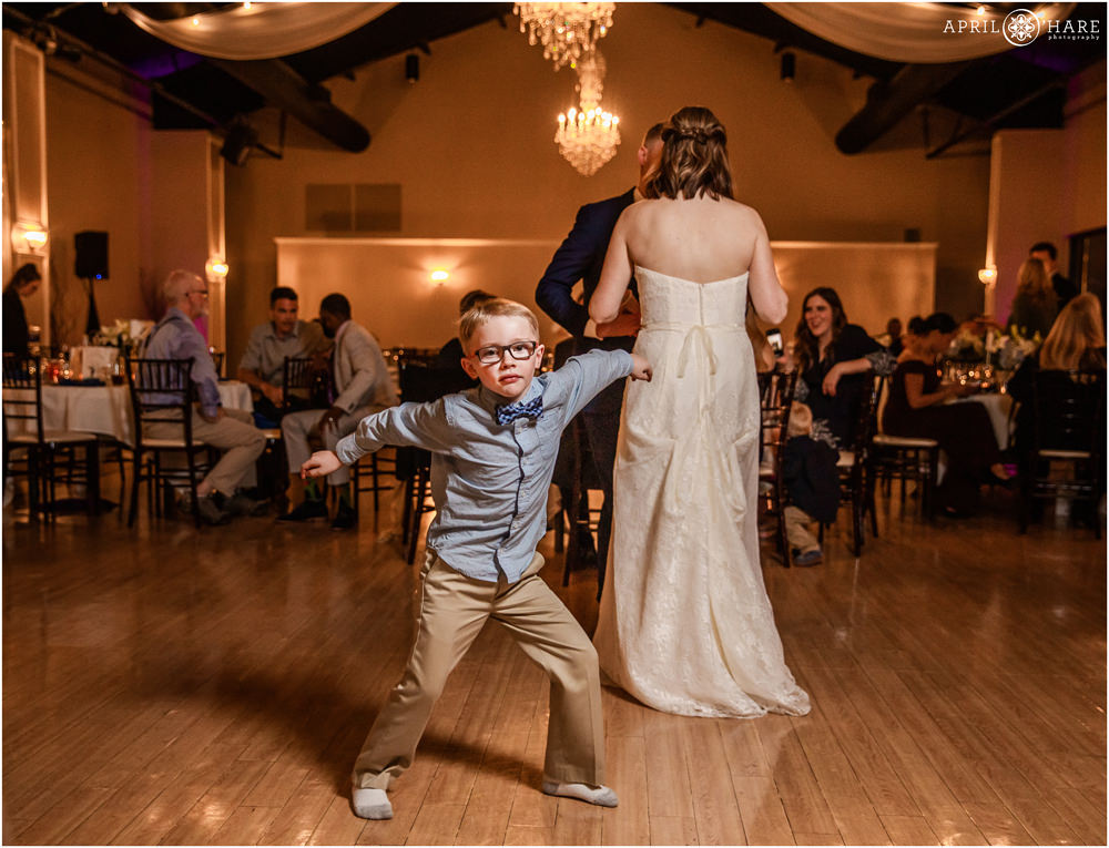 Little boy wearing glasses dances on a wedding dance floor