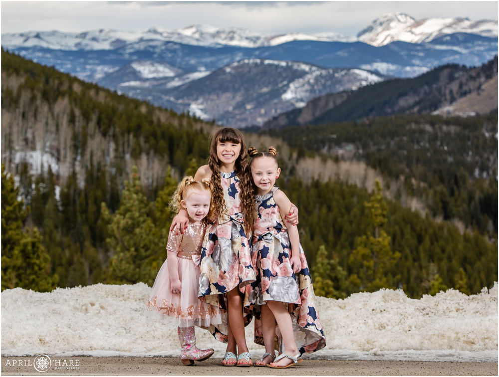 Three young sisters pose for photos with a pretty mountain backdrop in Colorado