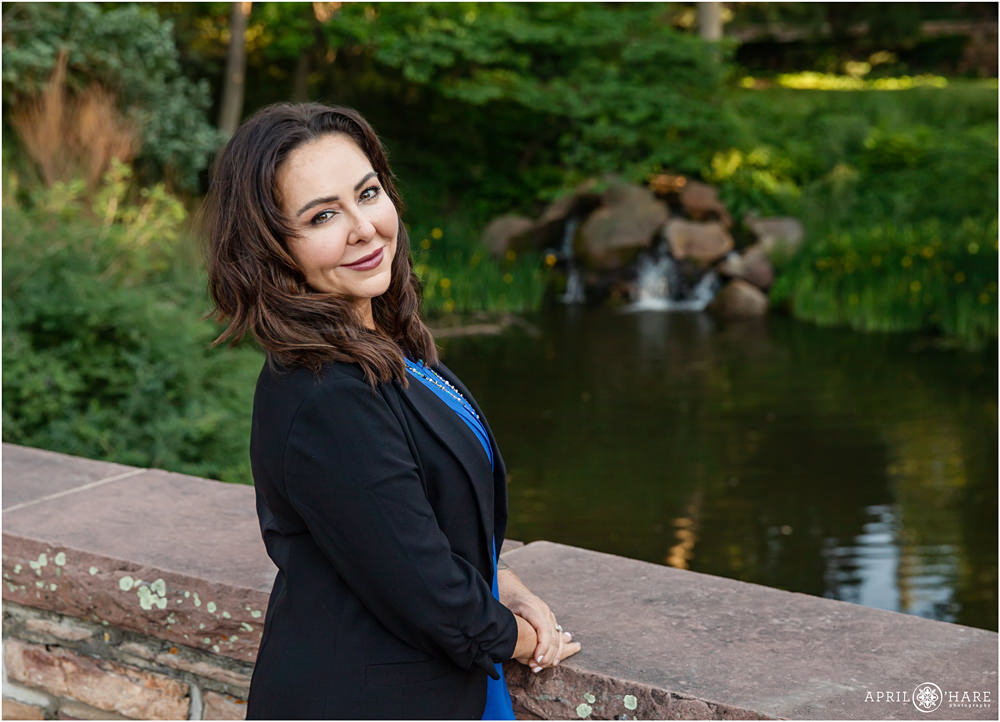 Woman poses for a business headshot portrait with waterfall backdrop at CU Boulder