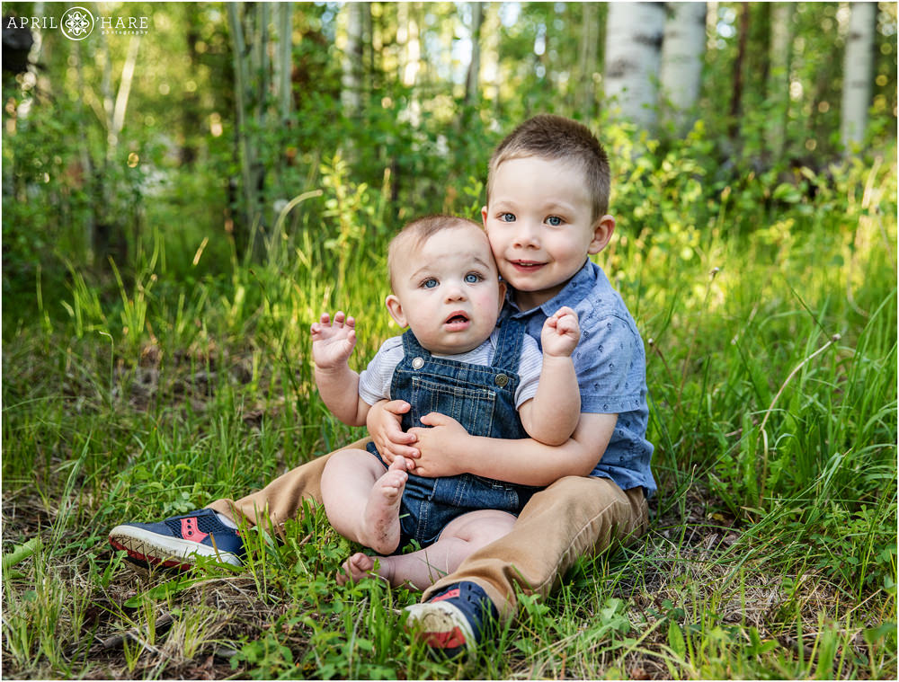 Sweet photo of baby boy with his 3 year old brother in a Colorado mountain forest