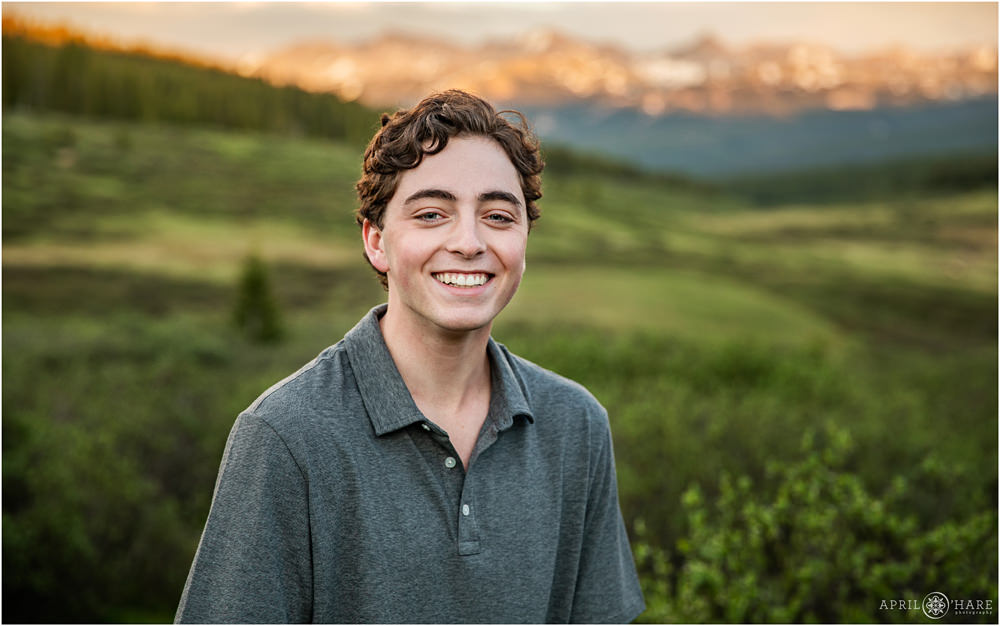 A teenage boy poses in front of a sunset mountain backdrop on Shrine Pass