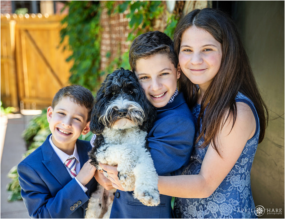 Sweet photo of siblings all together with their dog on the day of their B'nai Mitzvah in their Denver backyard