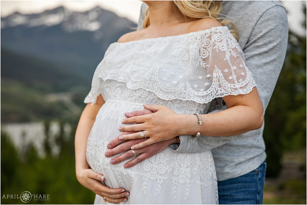 A close up photo of a pregnant woman with her husband as they cradle her pregnant belly at her Colorado maternity photography session