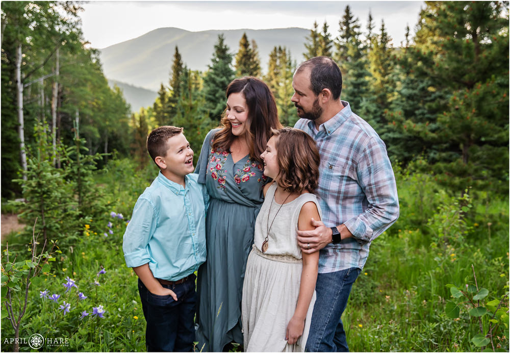 Candid happy family photo in the mountains of Colorado during summer for a family of four wearing blue and teal