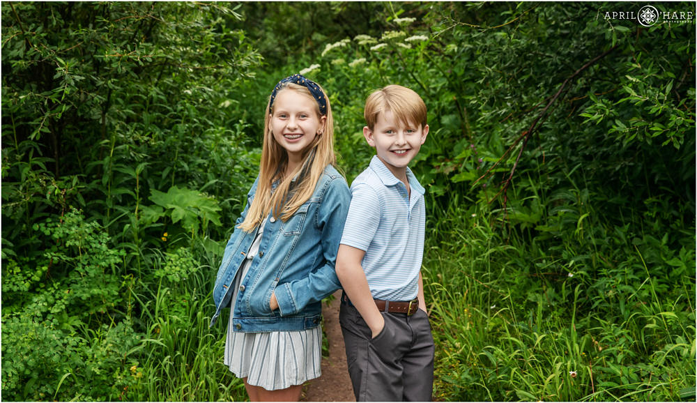 A young brother and sister pose for a picture back to back along a trail at Maroon Bells in Aspen