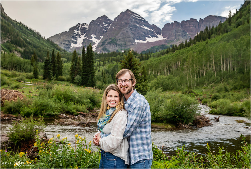 A cute couple pose in front of Maroon Creek at Maroon Bells in Aspen Colorado during summer