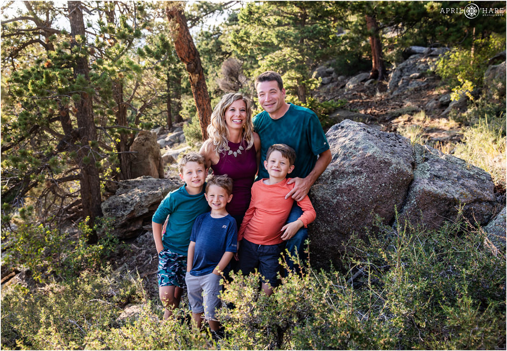 A family of 5 with 3 young boys pose in a the woods of Estes Park Colorado