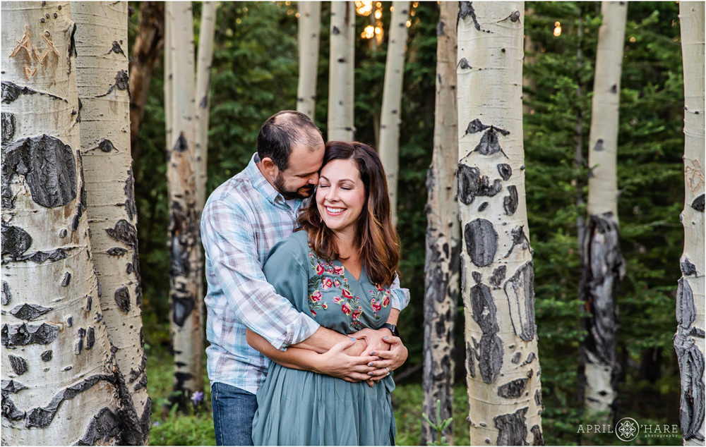 A father snuggles his wife at their Colorado family portrait session in an aspen tree forest