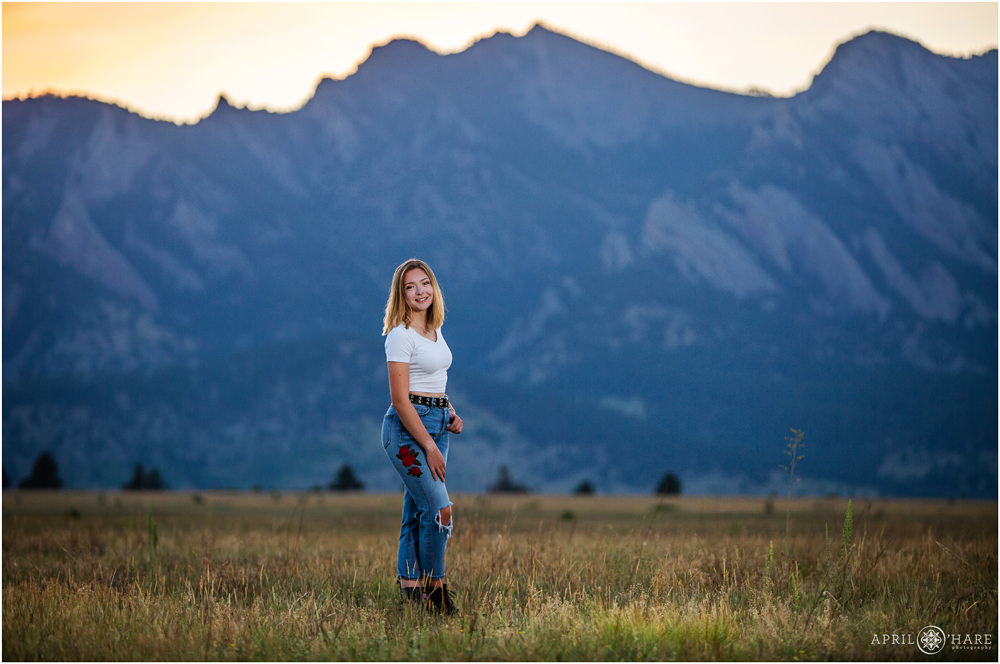 Boulder Senior Portraits with huge mountain backdrop in a grassy field in Boulder CO