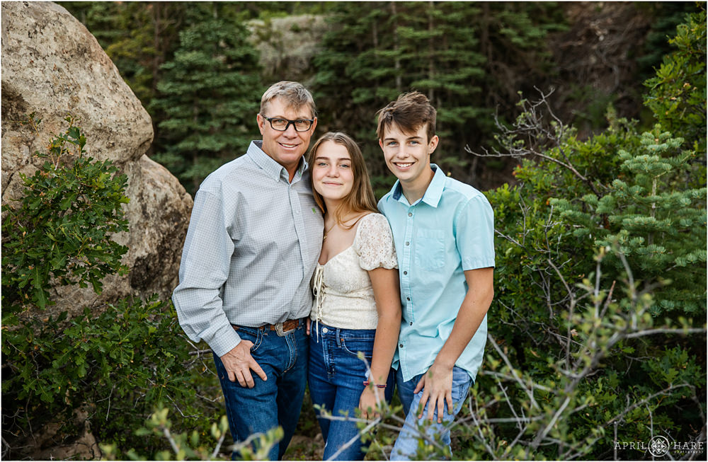 A dad with his two teenage children pose together with a beautiful Spanish peaks forest backdrop at Lover's Leap