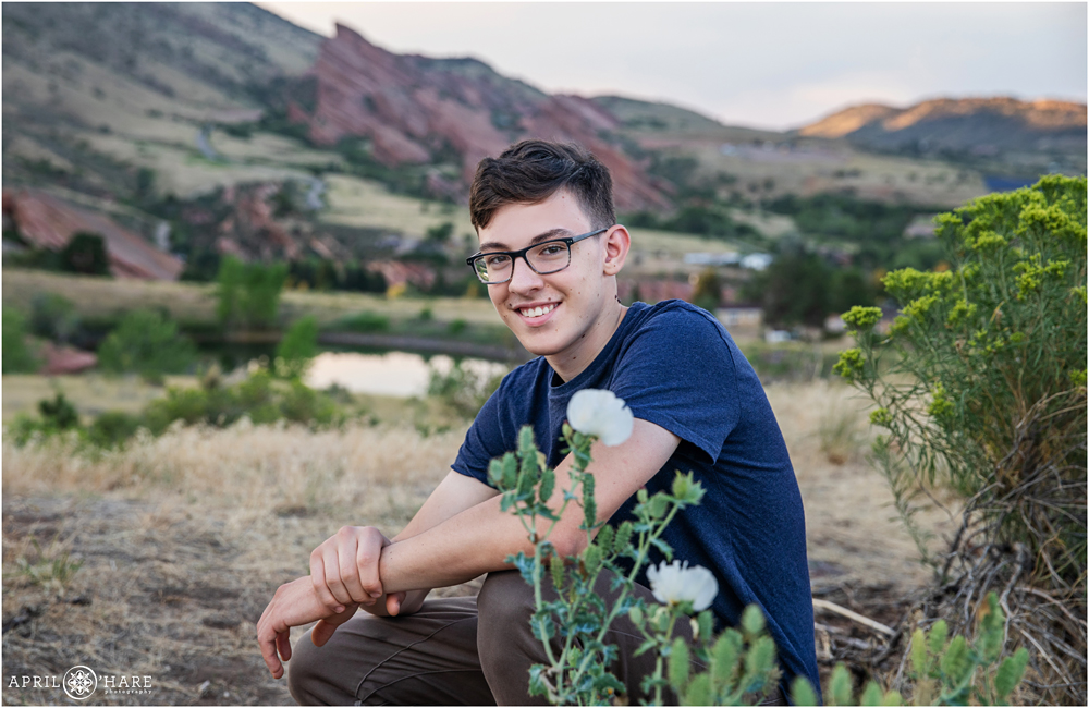 Senior Portrait for a boy wearing dark blue tshirt with white cactus flower in foreground at East Mount Falcon Trailhead
