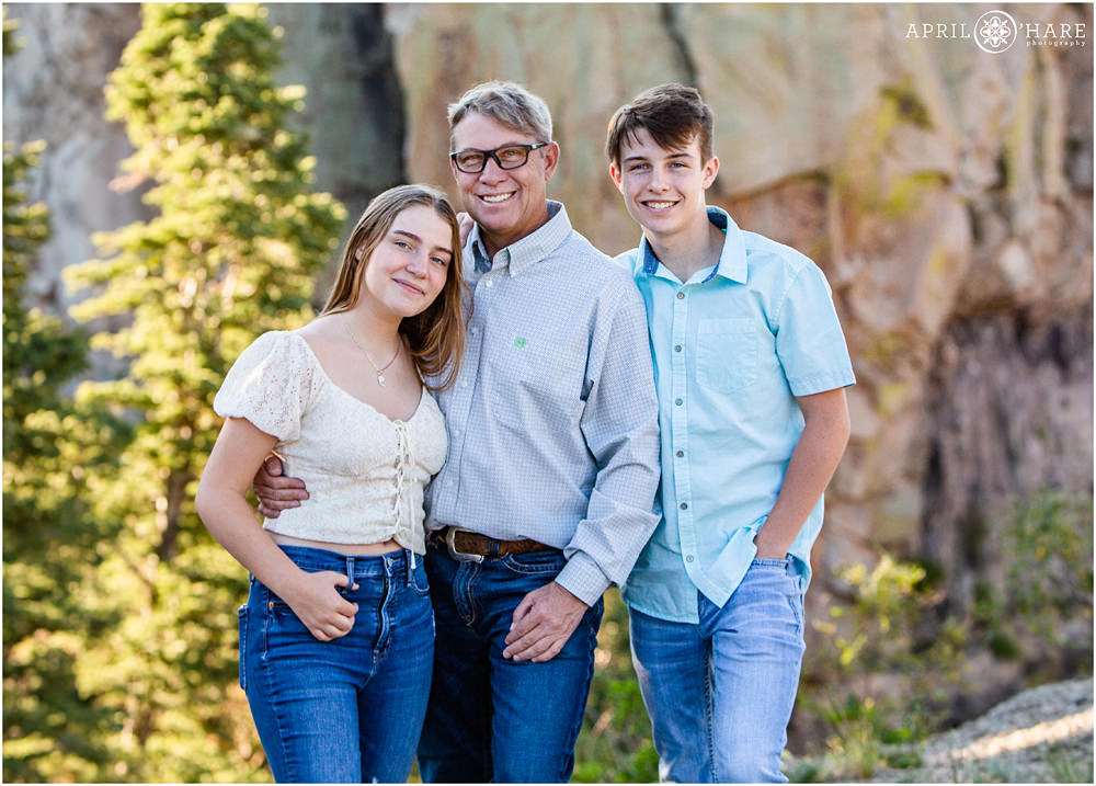 A dad poses for a picture with his two teenage kids at Lovers Leap in Colorado