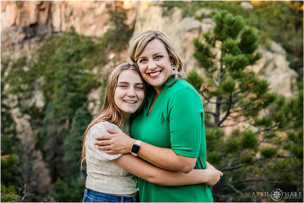 Beautiful portrait of a mom with her teenage daughter hugging in front of a pretty backdrop at Lover's Leap in Southern Colorado