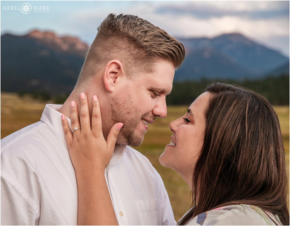 A recently engaged couple show off the engagement ring in a romantic photo at Moraine Park in RMNP