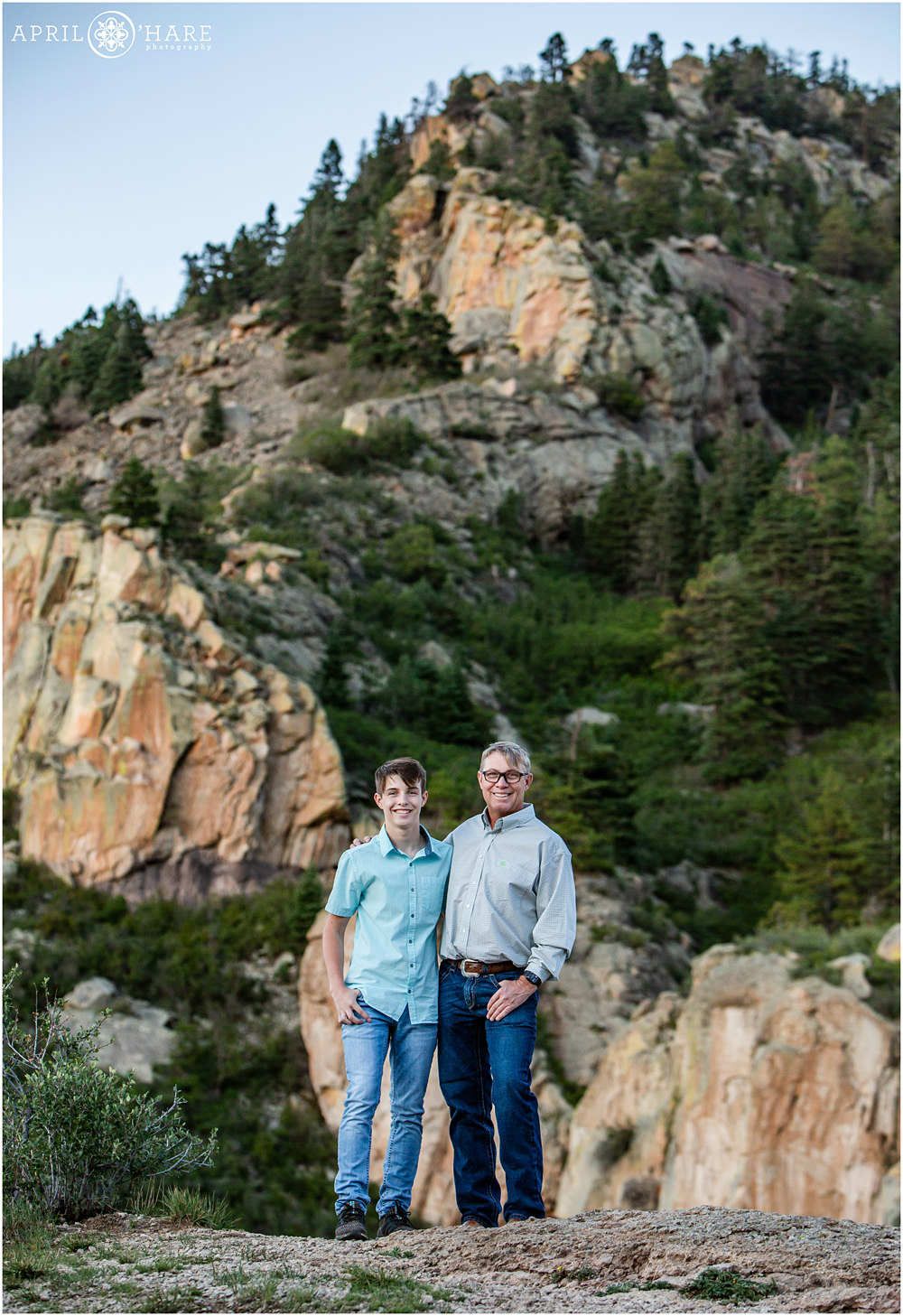 A dad poses with his son with a beautiful rocky cliff backdrop at Lovers Leap in Southern Colorado