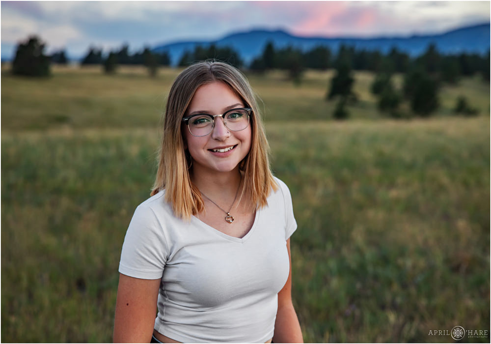 Smiling Senior Girl with Ombre hair wearing glasses and white tshirt at Flatirons Vista Trailhead at Sunset